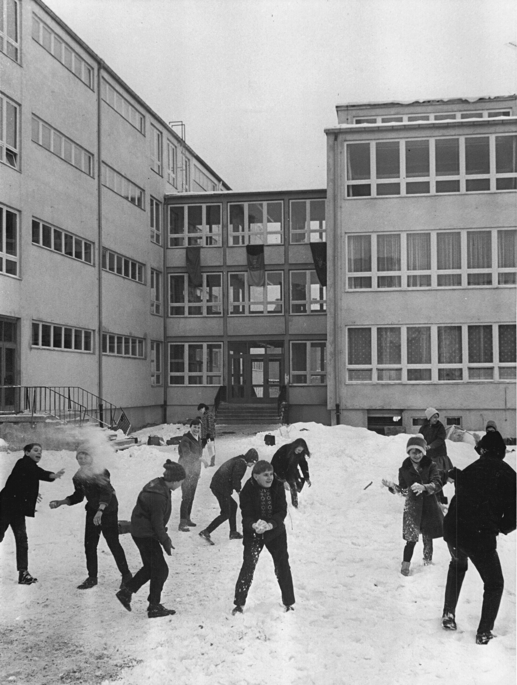 Kinder bei einer Schneeballschlacht vor dem Schulgebäude, Polytechnische Oberschule in Halle-Neustadt 1968